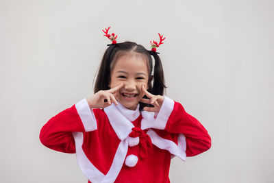 Portrait of smiling young woman using mobile phone while standing against wall