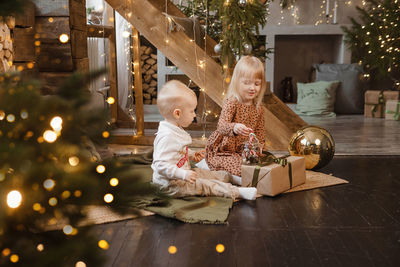Little brother and sister play on christmas eve in a beautiful house decorated for the new ear