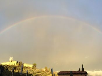Rainbow over buildings in city against sky