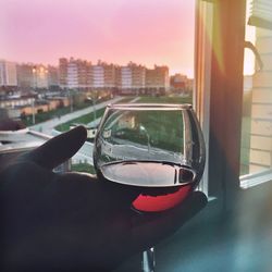 Close-up of hand holding drink against cityscape