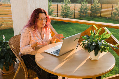 Portrait of young woman using mobile phone while sitting on table