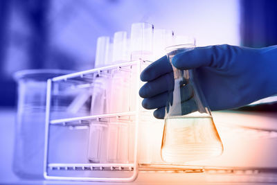 Cropped hand of scientist wearing glove holding conical flask in laboratory