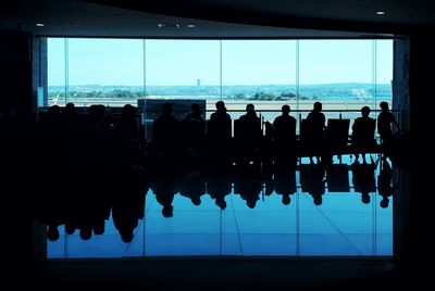 Silhouette people looking at view of window