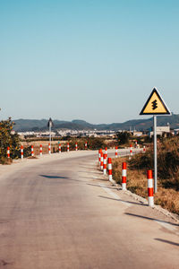 Road sign on street against clear blue sky