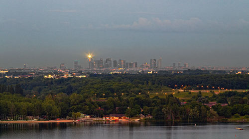 Scenic view of river by illuminated buildings against sky