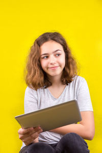 Portrait of smiling girl holding yellow camera