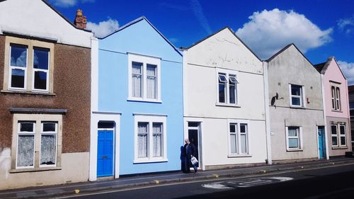 Woman walking on building against blue sky