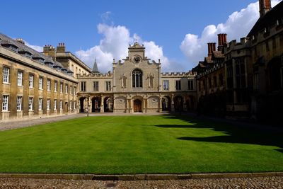 Lawn in front of historic building against sky