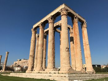 Low angle view of zeus temple against blue sky on sunny day