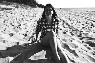 Portrait of woman sitting on sand at beach