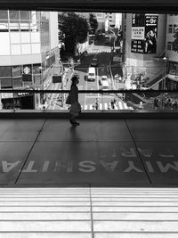 Rear view of woman walking on glass in city