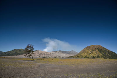 Scenic view of landscape and mountains against blue sky