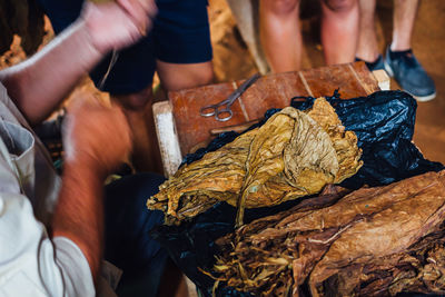 Cropped image of vendor with tobacco leaf at table