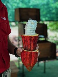 Midsection of man holding ice cream cone outdoors