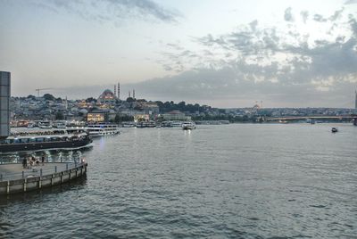 City at waterfront against cloudy sky