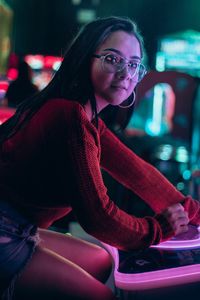 Portrait of woman sitting in illuminated room