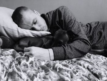 Man with dog sleeping on bed at home