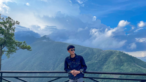 Young man on mountain against sky