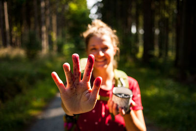 Portrait of woman showing stain on hand in forest