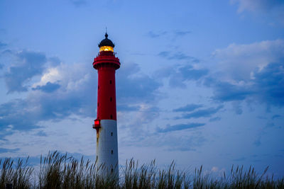 Low angle view of lighthouse by building against sky