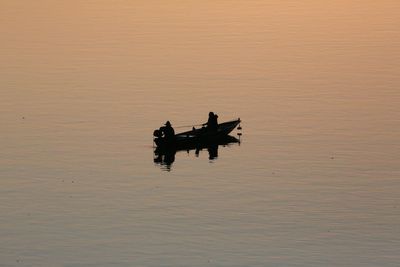 Silhouette of boat sailing in sea at sunset