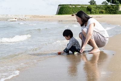 Rear view of mother and daughter on beach