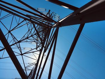 Low angle view of electricity pylon against blue sky