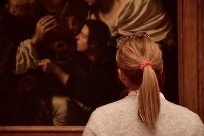 Rear view of woman looking at picture frame