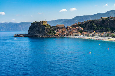 Scenic view of sea and mountains against blue sky