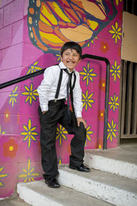 Portrait of smiling boy standing against wall