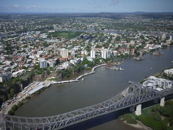 Metallic bridge over river in city against sky