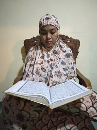 Portrait of a young woman sitting on book