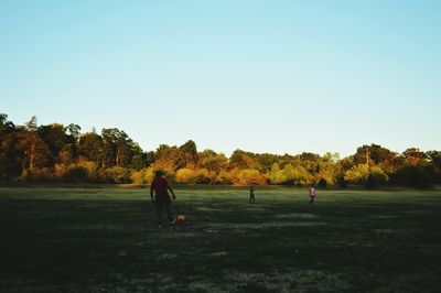 People playing soccer on field against clear sky