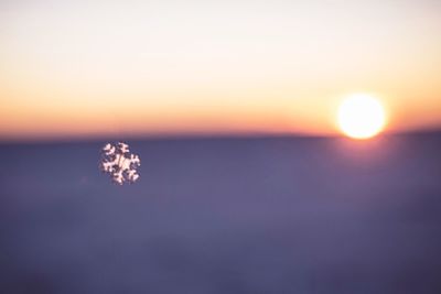 Sun shining on snow against sky during sunset