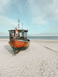 Fishing boat on beach against sky