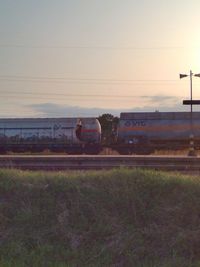 Train on field against sky during sunset