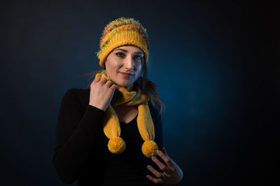 Portrait of young woman against black background