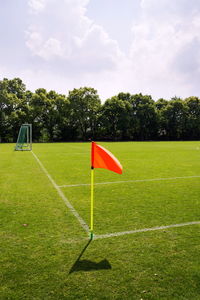 Red umbrella on field by trees against sky