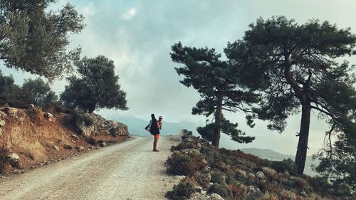 Rear view of man walking on road against sky