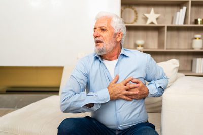 Portrait of senior man sitting on bed at home