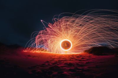 Man spinning wire wool at beach during night