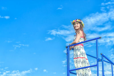 Low angle view of woman looking away against blue sky