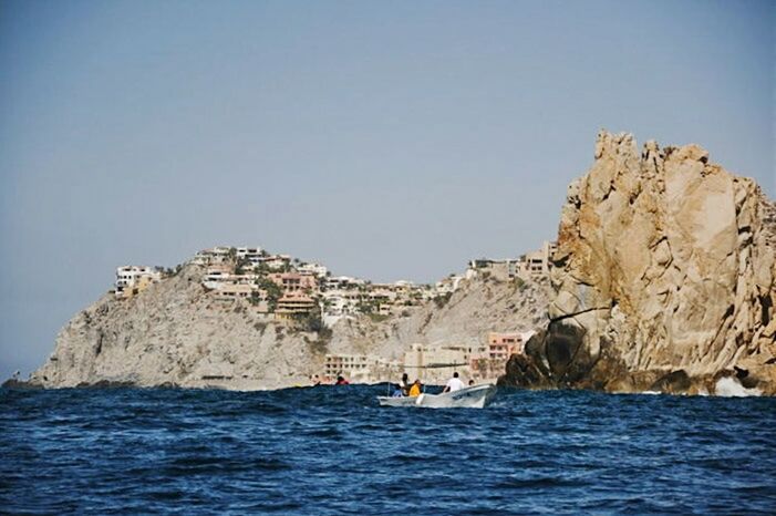 sea, water, clear sky, waterfront, nautical vessel, blue, transportation, rock formation, copy space, mode of transport, scenics, boat, cliff, rock - object, tranquility, tranquil scene, nature, beauty in nature, horizon over water, travel