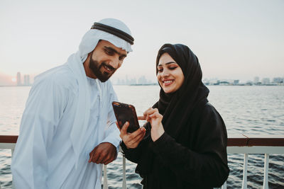 Young man using phone while looking at camera