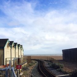 Railroad tracks at beach against sky