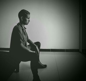 Young man looking away while sitting on table