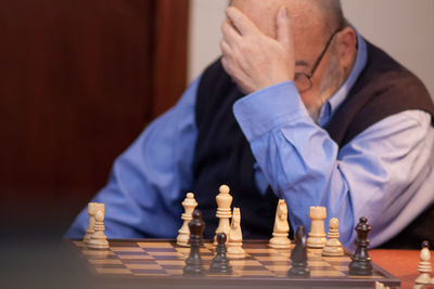 Senior man leaning by chess on table