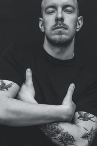 Portrait of young man sitting against black background