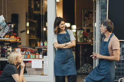 Male and female employees talking at entrance of deli