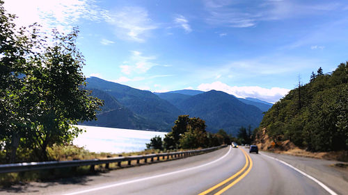 Road by trees against sky